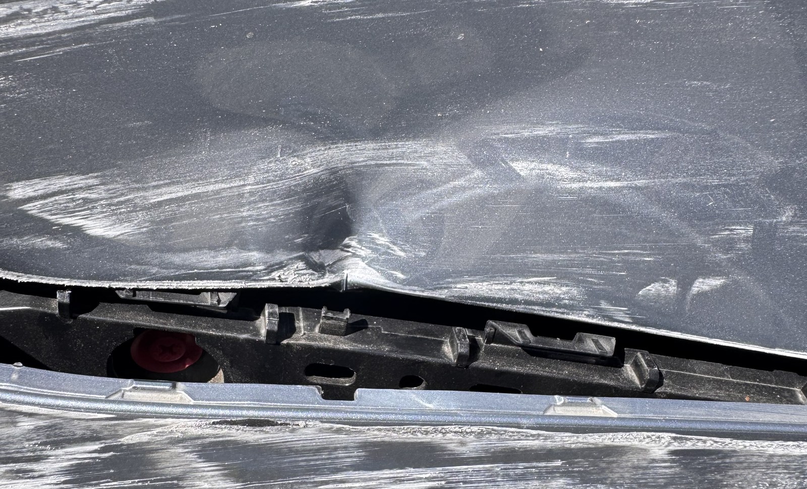 Close view of impact damage around a vehicle bumper and adjoining panel